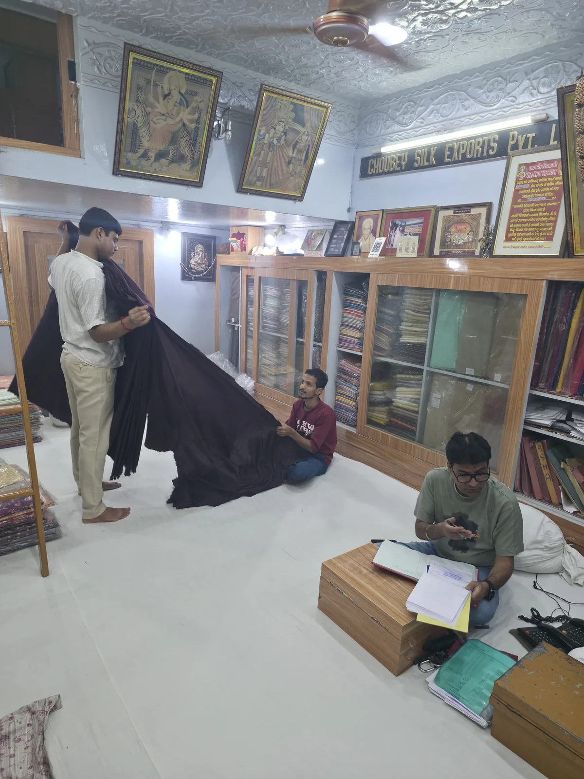 Choubey Silk staff presenting fabric inside the wholesale silk showroom in Varanasi